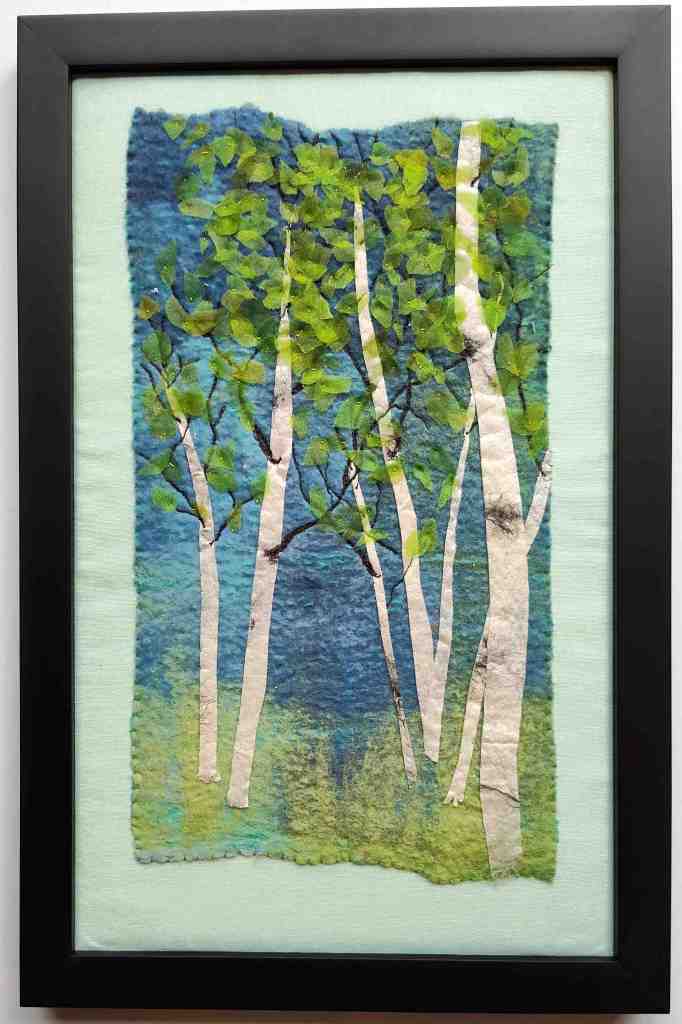 Framed textile artwork with spring time birch grove and hidden lake in the distance.